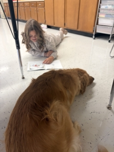 EF Student Reading with Sasha the dog.